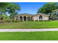 Charming single-story home featuring a well-manicured lawn, arched entryway, and lush landscaping at 2501 Oak Landing Dr, Brandon, FL 33511