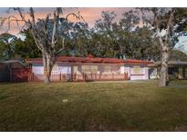 Charming single-story home with red tile roof, wooden fence, and lush front lawn at 4929 Avery Rd, New Port Richey, FL 34652