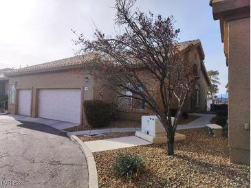 Tan stucco exterior with two-car garage and landscaping at 4727 Wild Draw Dr, North Las Vegas, NV 89031