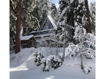 A-frame cabin nestled among snow-covered trees, offering a serene winter retreat with unique architectural charm at 4205 Mont Blanc Way, Las Vegas, NV 89124