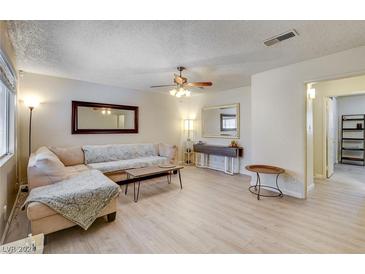 Bright living room with L-shaped sofa, light wood floors, and ceiling fan at 3841 Daisy St # 18, Las Vegas, NV 89119