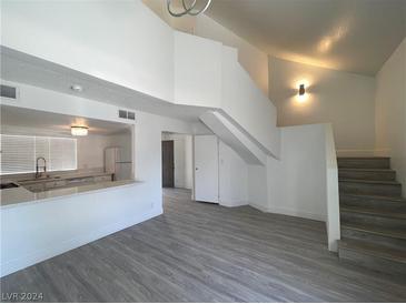 Bright open-concept living room with a modern kitchen view, sleek flooring, and stairs at 4281 White Sands Ave, Las Vegas, NV 89121