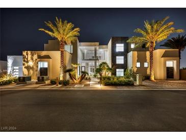 Striking modern home featuring palm trees, stone accents, and an inviting entrance at nighttime at 9760 Solar Ave, Las Vegas, NV 89149