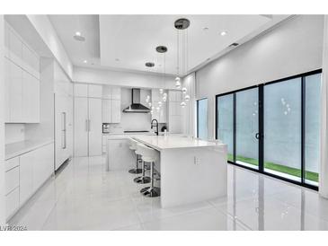 Bright, all-white kitchen features a large center island, pendant lighting, and modern appliances at 9760 Solar Ave, Las Vegas, NV 89149