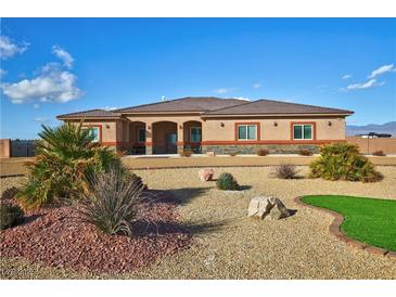 Single story home featuring desert landscaping, a neutral color palette and mature shrubbery at 1120 W Gray Fox Way, Pahrump, NV 89048