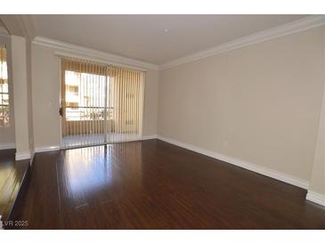 Bright living room with dark hardwood floors and access to a balcony at 270 E Flamingo Rd # 107, Las Vegas, NV 89169