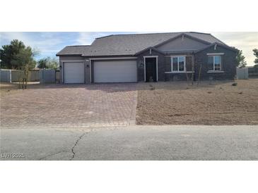 Single-story home with two-car garage and landscaped yard at 4761 E Sandalwood Dr, Pahrump, NV 89061