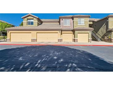 Low angle of building exterior with multi-car garage doors and desert landscaping at 6868 Sky Pointe Dr # 2039, Las Vegas, NV 89131