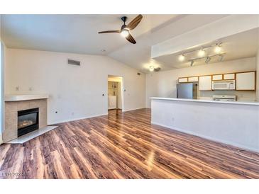 Inviting living room featuring hardwood floors, a fireplace, and an open layout to the kitchen at 4960 Harrison Dr # 214, Las Vegas, NV 89120