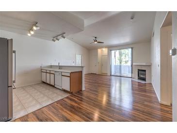 Open-concept living area features hardwood floors, fireplace, and sliding glass doors to balcony at 4960 Harrison Dr # 214, Las Vegas, NV 89120