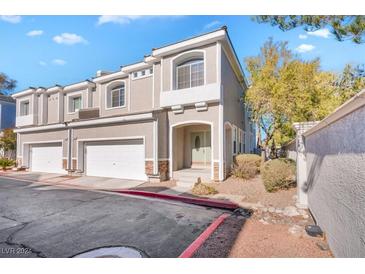 Tan three-story townhome with two-car garage, landscaping, and a red curb at 2410 Encouraging Ct, Henderson, NV 89052