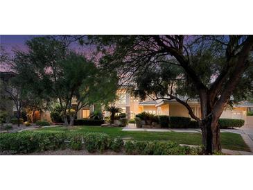 Inviting front yard featuring lush landscaping and a charming home exterior at twilight at 605 Canyon Greens Dr, Las Vegas, NV 89144