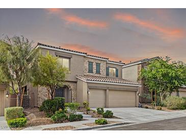 Beautiful two-story home with a stone facade, desert landscaping, and a two-car garage at sunset at 9143 Irish Elk Ave, Las Vegas, NV 89149