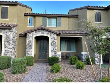 Charming townhome featuring stone accents, covered porch, landscaped yard, and neutral color palette at 3245 Montage Dr, Henderson, NV 89044