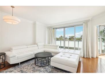 Bright living room with a white leather couch, hardwood floors and access to a balcony at 322 Karen Ave # 206, Las Vegas, NV 89109