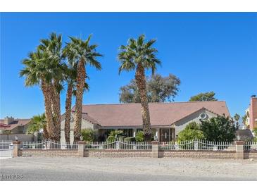 Charming single-story home featuring lush palm trees, a brick-and-wrought-iron fence, and a well-manicured front yard at 485 Sari Dr, Las Vegas, NV 89110