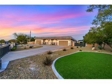 Single story home with large garage, desert landscaping, and green grass at 647 Foxhall Rd, Henderson, NV 89002