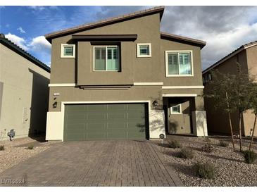 Inviting two-story home with neutral exterior, green garage door and brick driveway at 7156 Woodrow Ranch St, Las Vegas, NV 89166
