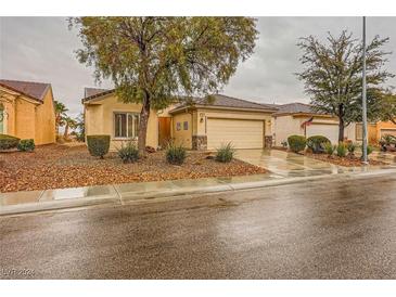 Charming single-story home featuring a well-manicured front yard with mature trees and a two-car garage at 7804 Island Rail Dr, North Las Vegas, NV 89084