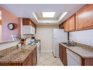 Efficient kitchen featuring granite countertops, wooden cabinetry, and stainless steel appliances under a skylight at 4200 S Valley View Blvd # 3030, Las Vegas, NV 89103