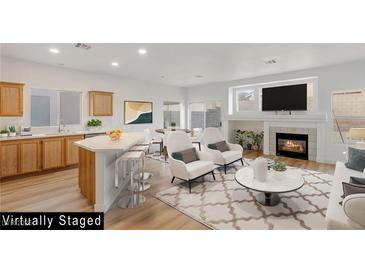 Open living room with fireplace, light wood floors, white walls, and bar seating into the kitchen at 7936 Pinnochio Ave, Las Vegas, NV 89131