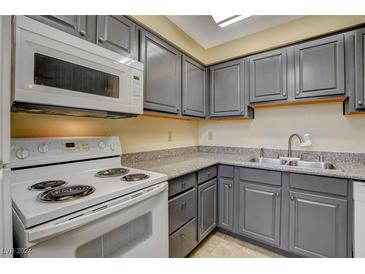 Cozy kitchen with gray cabinets, laminate countertops, and white appliances at 5301 River Glen Dr # 210, Las Vegas, NV 89103