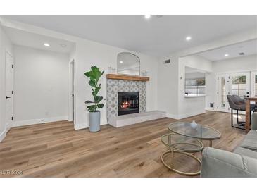 Bright living room with fireplace, hardwood floors, and a stylish glass coffee table at 2628 Starfish Ct, Las Vegas, NV 89128