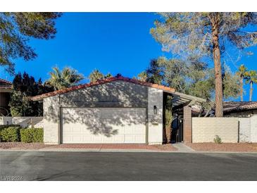 Single story home with a brick-paved driveway, a white garage door, and a terra cotta colored roof at 3012 Plaza De Rosa, Las Vegas, NV 89102