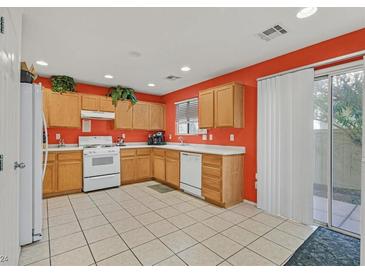 Bright kitchen features light wood cabinets, white appliances, and orange walls at 6058 Ambleshire Ave, Las Vegas, NV 89139