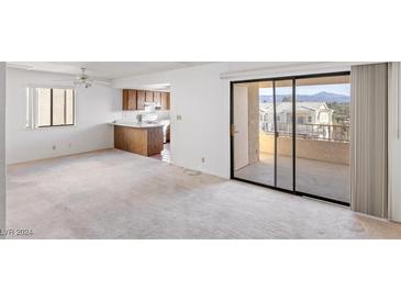 Bright living room featuring a sliding glass door to a balcony and an adjacent kitchen with tiled floor at 1965 Scimitar Dr # 0, Henderson, NV 89014