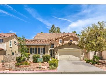 Two-story house with tan exterior, tile roof, and landscaped front yard at 1590 Sabatini Dr, Henderson, NV 89052