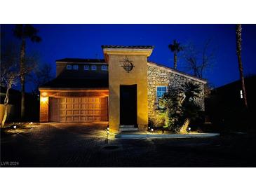 Charming home with stone accents, illuminated by landscape lighting at twilight at 1282 Calcione Dr, Henderson, NV 89011