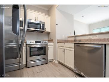 Modern kitchen features stainless steel appliances and light wood-style flooring at 2151 Hussium Hills St # 207, Las Vegas, NV 89108