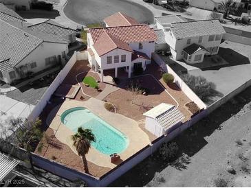 Aerial view of a fenced backyard, featuring a private pool with a desert landscape and a detached shed at 504 Landra Ln, Henderson, NV 89015