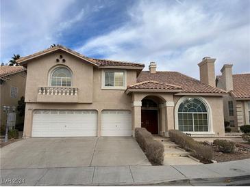 Tan two-story house with three-car garage, arched entryway, and landscaped walkway at 2412 Eagleridge Dr, Henderson, NV 89074