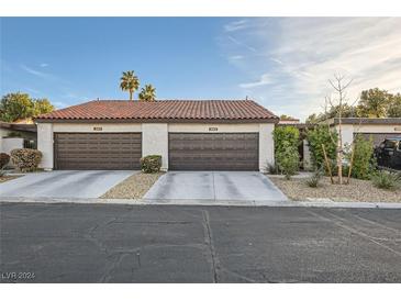 Attached two-car garage with brown doors, tile roof, and desert landscaping at 3143 Sonata Dr, Las Vegas, NV 89121