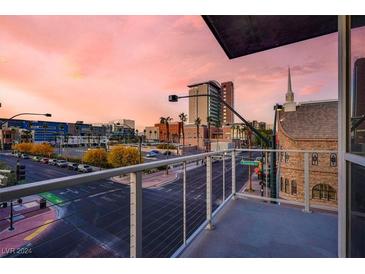 City view from balcony with sidewalks and street, and a colorful skyline with pink clouds at 353 E Bonneville Ave # 313, Las Vegas, NV 89101