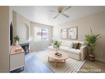 Bright living room featuring a fireplace, ceiling fan, and large windows at 8455 W Sahara Ave # 154, Las Vegas, NV 89117