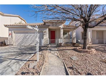 House exterior featuring a red door, two-car garage, and landscaped walkway at 5372 Polo Grounds St, Las Vegas, NV 89148