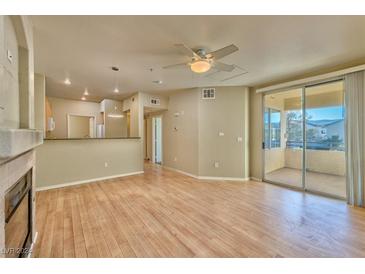 Bright living room with hardwood floors, fireplace, and access to balcony at 7151 S Durango Dr # 214, Las Vegas, NV 89113