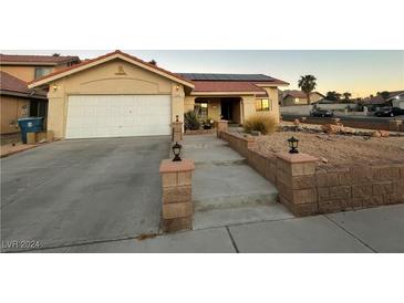 Single-story house with attached garage, solar panels, and landscaped walkway at 1550 Desertaire Way, Las Vegas, NV 89110