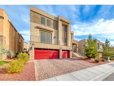 Modern three-story home with red double garage doors and landscaped yard at 9830 Wild Coyote Ct, Las Vegas, NV 89141