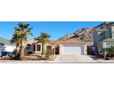 Single-story house with a two-car garage, palm trees, and mountain views at 1940 Whiton St, Las Vegas, NV 89156