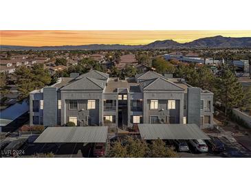 Two-story condo with a gray exterior, covered parking, and mountain views at 2201 Ramsgate Dr # 327, Henderson, NV 89074