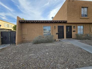 Front view of a light brown stucco duplex with a small front yard and walkway at 6311 W Washington Ave, Las Vegas, NV 89107