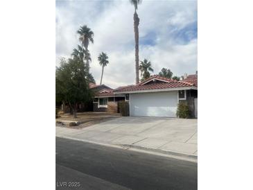 Single story home with tile roof, two-car garage, and desert landscaping at 7393 Puritan Ave, Las Vegas, NV 89123