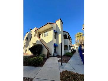 Condo building with desert landscaping, walkway, and blue awnings on a sunny day at 6137 W Oakey Blvd # A, Las Vegas, NV 89146