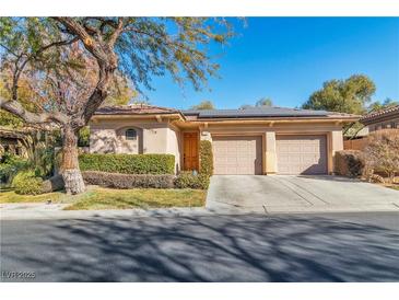 Tan two-story house with solar panels, two-car garage, and well-manicured landscaping at 120 Emerald Dunes Cir, Henderson, NV 89052