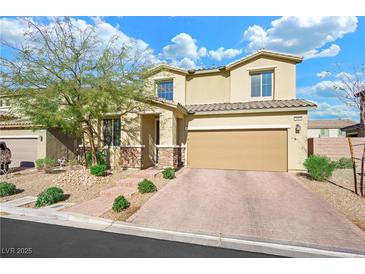 Two-story house with tan exterior, brick driveway and landscaping at 3094 Isle Dr, Las Vegas, NV 89141