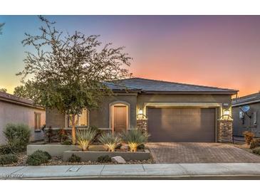 Single-story home with a two-car garage, landscaped yard, and brick driveway at 5433 Strawberry Swing St, North Las Vegas, NV 89081